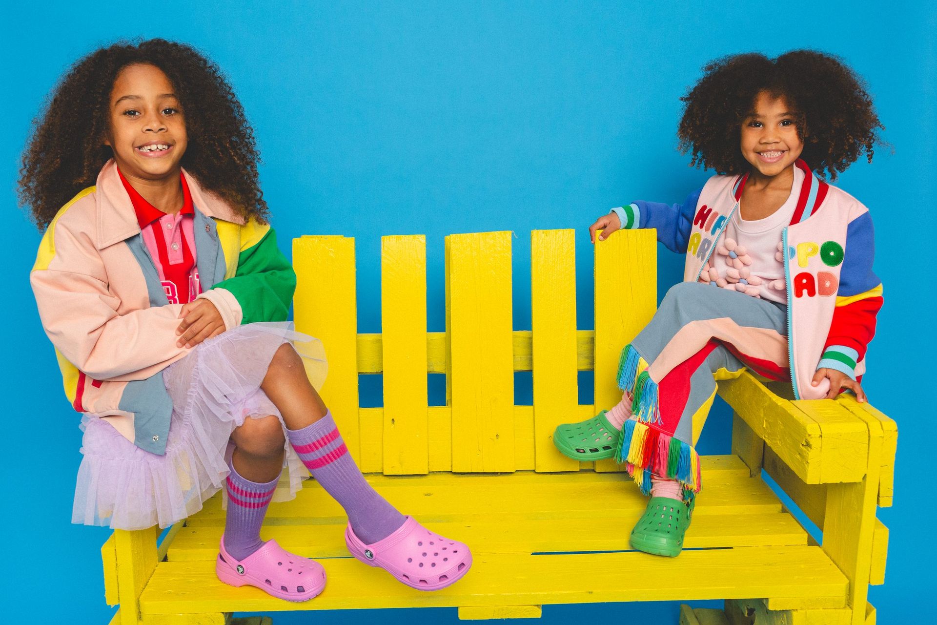 Two children in colourful jackets on a yellow bench